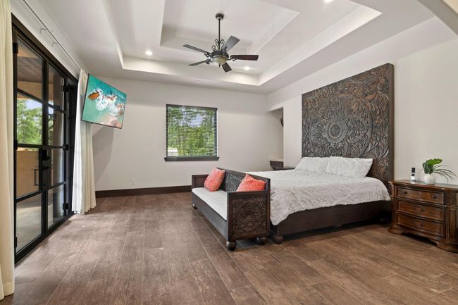 Primary bedroom with trey ceilings and double doors leading to patio/pool area. | Image 25