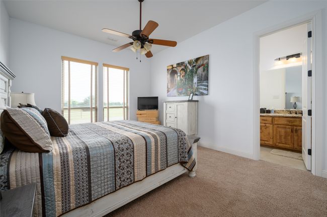 Bedroom with ensuite bathroom, a sink, ceiling fan, light carpet, and baseboards | Image 23