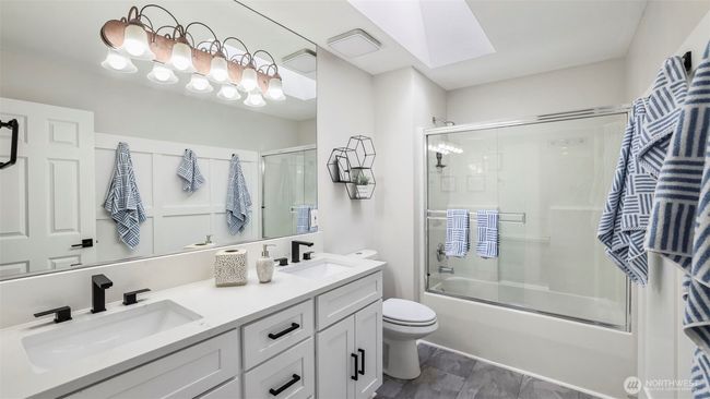 This upstairs full bathroom features a double sink with sleek white countertops and a skylight that fills the space with natural light | Image 26