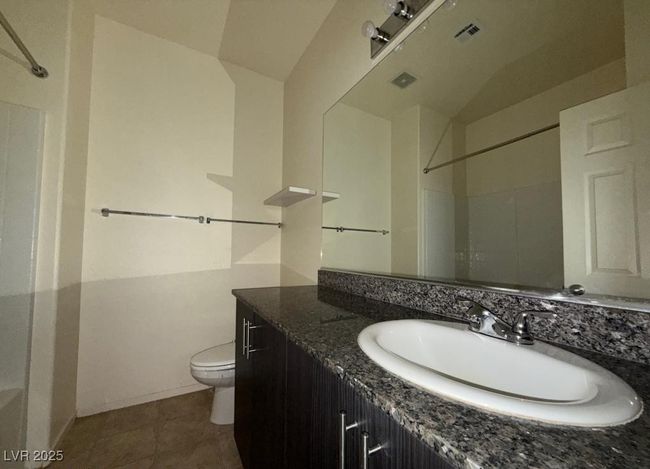 Bathroom featuring toilet, a shower, vanity, and visible vents | Image 7