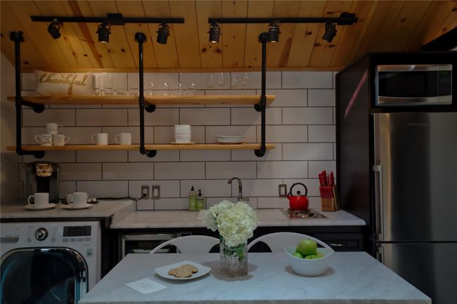Kitchen featuring wooden ceiling, open shelves, washer / dryer, stainless steel appliances, and decorative backsplash | Image 7