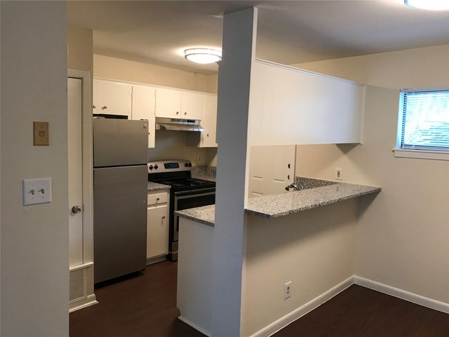 Kitchen with under cabinet range hood, dark wood-style flooring, a peninsula, and appliances with stainless steel finishes | Image 11