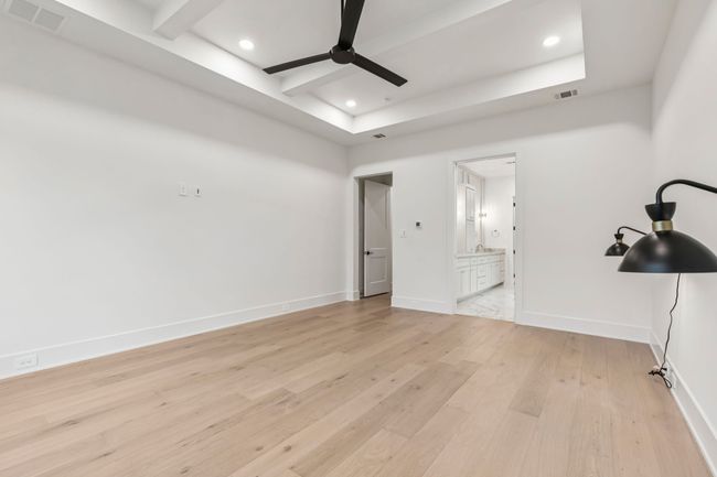 Unfurnished bedroom with light wood-style floors, connected bathroom, ceiling fan, recessed lighting, and beam ceiling | Image 15