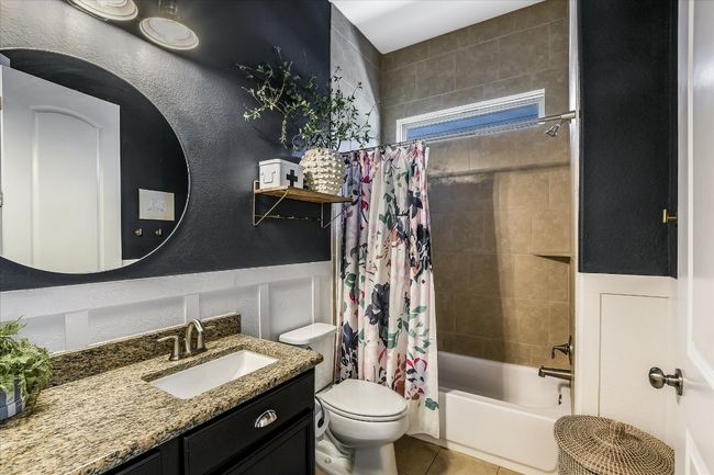 Full bathroom with toilet, shower / tub combo with curtain, a wainscoted wall, vanity, and tile patterned floors | Image 23