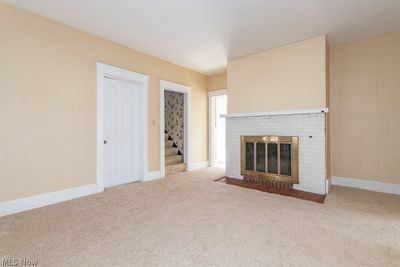 Unfurnished living room with light carpet and a brick fireplace | Image 3