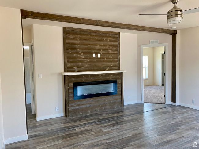 Unfurnished living room featuring wood finished floors, a glass covered fireplace, and ceiling fan | Image 4