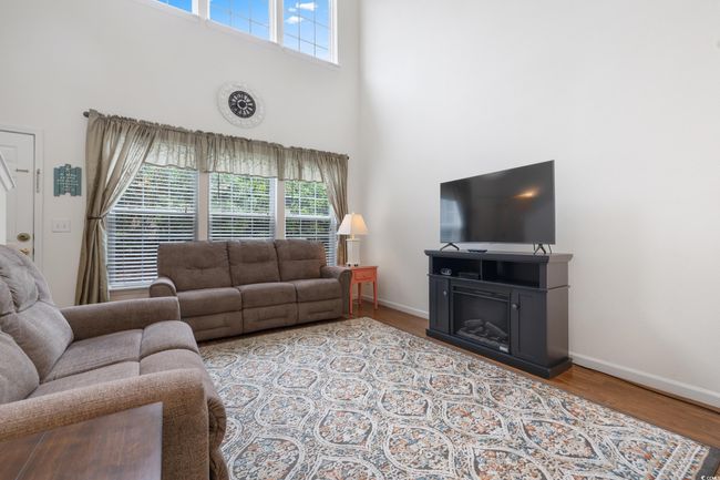 Living area with a towering ceiling, plenty of natural light, baseboards, and wood finished floors | Image 9