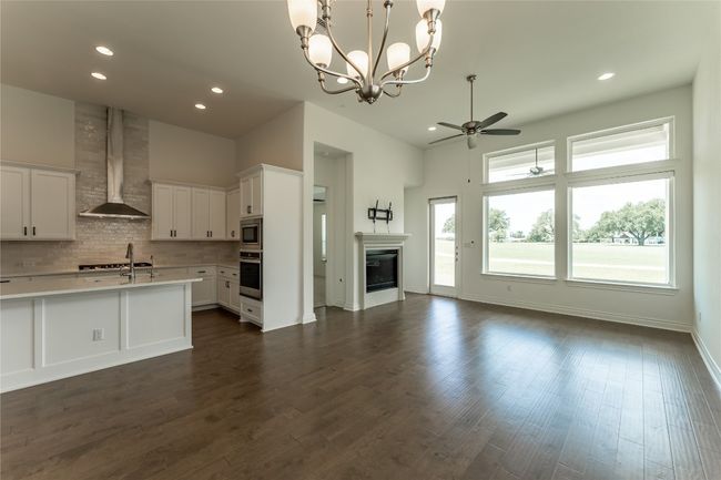 Kitchen with appliances with stainless steel finishes, wall chimney range hood, open floor plan, a ceiling fan, and light countertops | Image 20