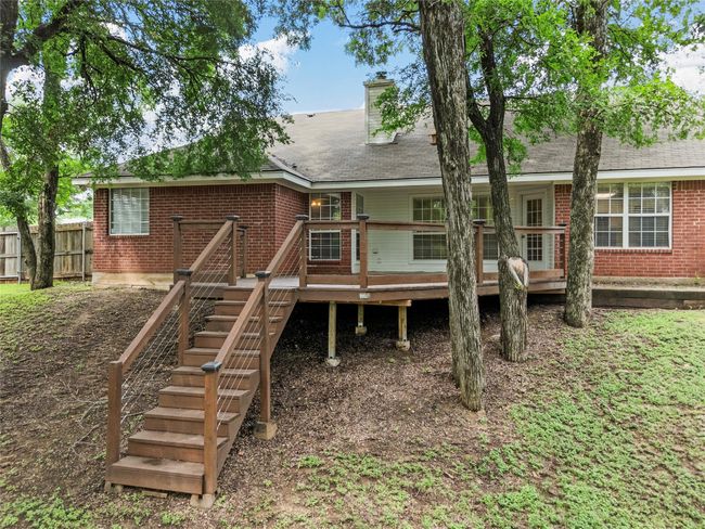 Rear view of house with brick siding, a deck, a chimney, and roof with shingles | Image 17