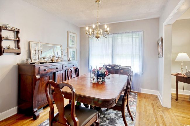 Dining space featuring a chandelier, light wood-style flooring, baseboards, and a textured ceiling | Image 11