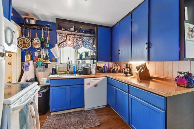 Kitchen with white appliances, blue cabinets, a sink, dark wood-style flooring, and light countertops | Image 18