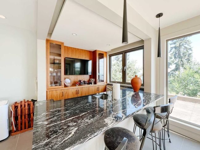 Kitchen with light tile patterned floors, dark stone countertops, healthy amount of natural light, and glass insert cabinets | Image 24