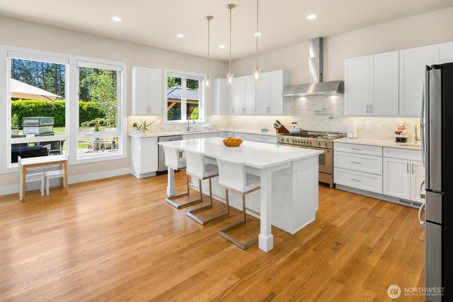 Pristine white kitchen of your dreams has tons of storage and the island becomes the ultimate gathering place while the chef is in action. | Image 8