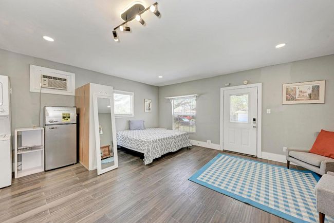 Bedroom with wood finished floors, freestanding refrigerator, recessed lighting, stacked washer / dryer, and baseboards | Image 33