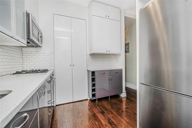 Kitchen with stainless steel appliances, dark wood-style floors, tasteful backsplash, white cabinetry, and modern cabinets | Image 13