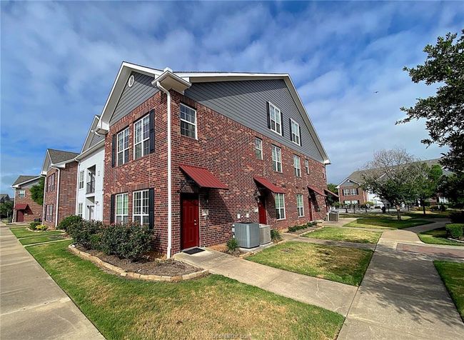 View of property exterior with brick siding, a lawn, central AC unit, and a residential view | Image 15
