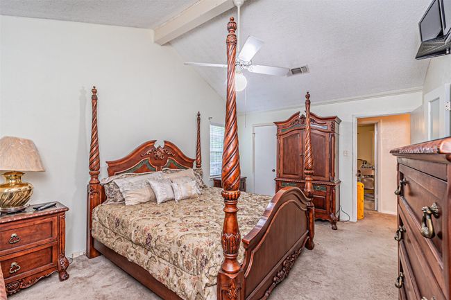 Bedroom with visible vents, vaulted ceiling with beams, light carpet, and a textured ceiling | Image 16