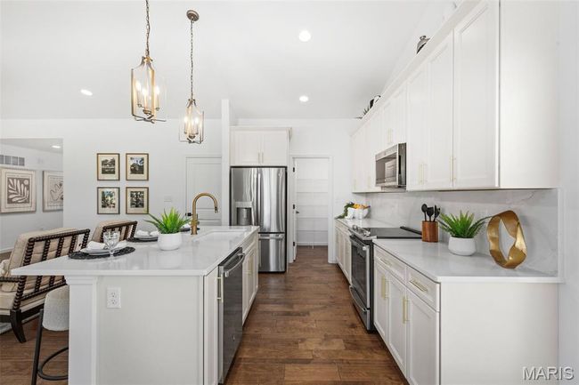 Kitchen featuring appliances with stainless steel finishes, a breakfast bar, an island with sink, a chandelier, and a sink | Image 14