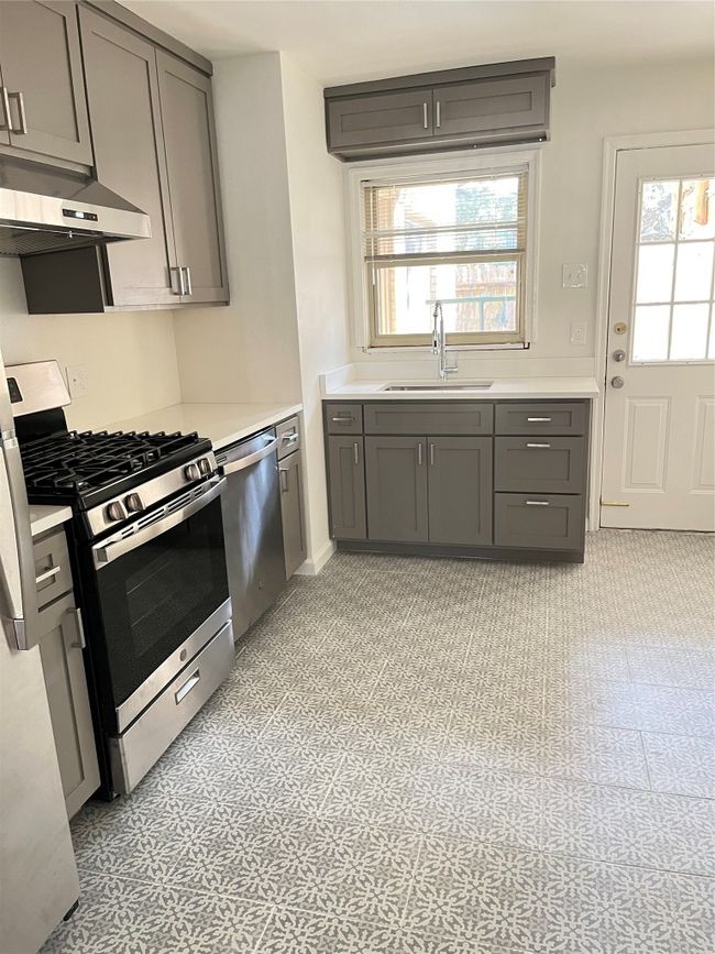 Kitchen featuring stove, dishwasher, a sink, and gray cabinets | Image 19