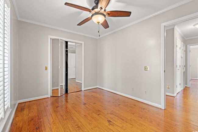 Unfurnished bedroom featuring hardwood / wood-style floors, a closet, crown molding, and ceiling fan | Image 37