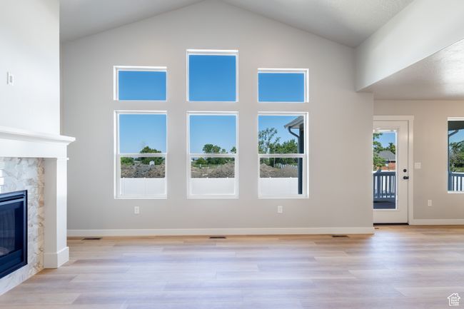Unfurnished living room featuring a fireplace, light wood finished floors, and high vaulted ceiling | Image 12