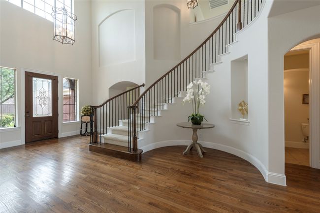 Foyer with arched walkways, a towering ceiling, wood finished floors, and stairway | Image 6