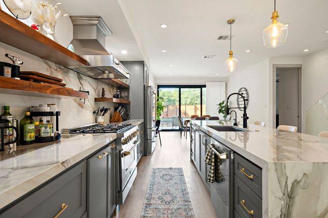 Kitchen featuring light wood finished floors, stainless steel appliances, open shelves, gray cabinets, and a sink | Image 7