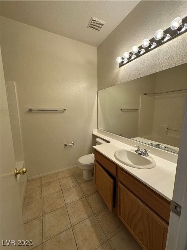 Full bathroom featuring tile patterned floors, vanity, toilet, a shower, and a textured ceiling | Image 22