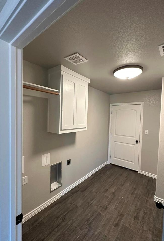 Laundry area featuring cabinet space, dark wood finished floors, a textured ceiling, and hookup for an electric dryer | Image 8