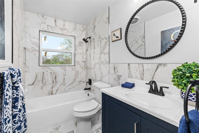 Full bath with marble finish floor, shower / tub combo with curtain, tile walls, toilet, and vanity | Image 24