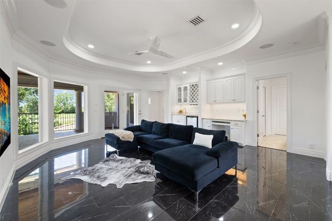Living area featuring a tray ceiling, baseboards, a ceiling fan, crown molding, and bar | Image 27