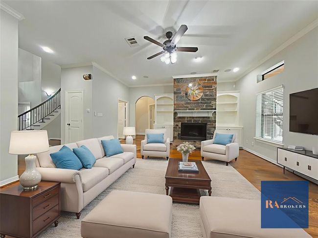 This cozy living room features a stone fireplace, built-in shelves, and hardwood floors. (virtually staged) | Image 12