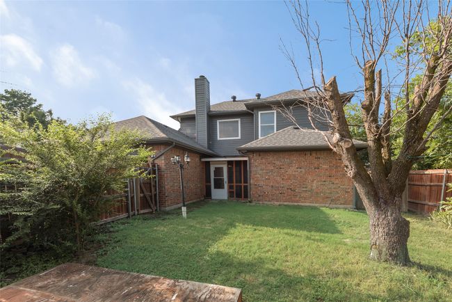 Rear view of house with a chimney, brick siding, and roof with shingles | Image 17