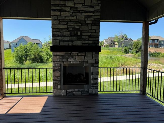 Wooden deck with an outdoor stone fireplace and a residential view | Image 16