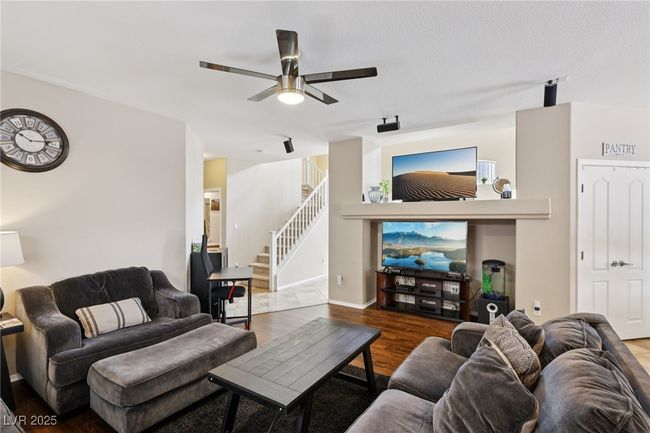 Living area featuring a ceiling fan, wood finished floors, and stairway | Image 18