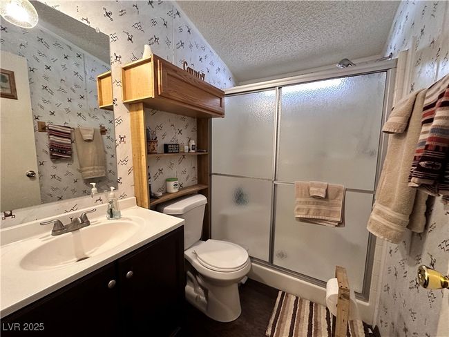 Bathroom featuring a shower stall, a textured ceiling, and wallpapered walls | Image 16