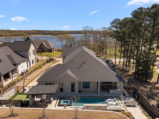 View of swimming pool with a fenced backyard, a pool with connected hot tub, a water view, and a patio | Image 33
