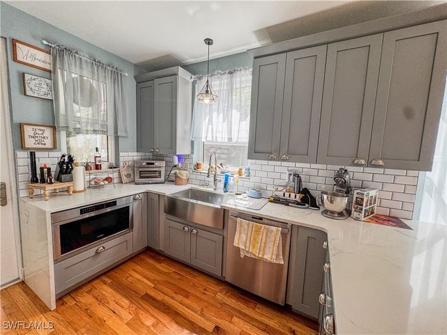 Kitchen with stainless steel dishwasher, gray cabinetry, a sink, and tasteful backsplash | Image 9