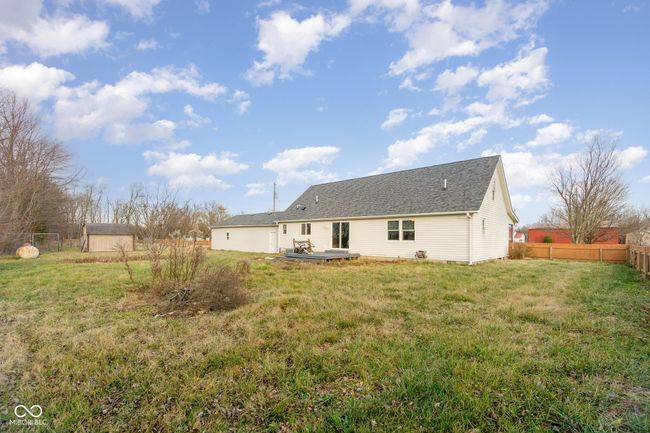 rear view of house featuring roof with shingles, an outdoor structure, fence, and a yard | Image 25