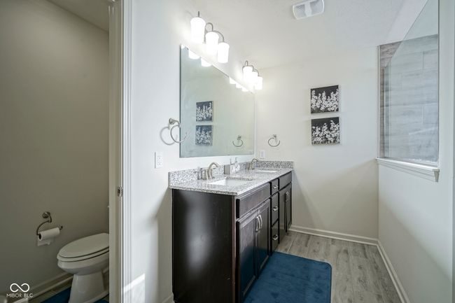 full bath with toilet, a sink, visible vents, double vanity, and wood finished floors | Image 38