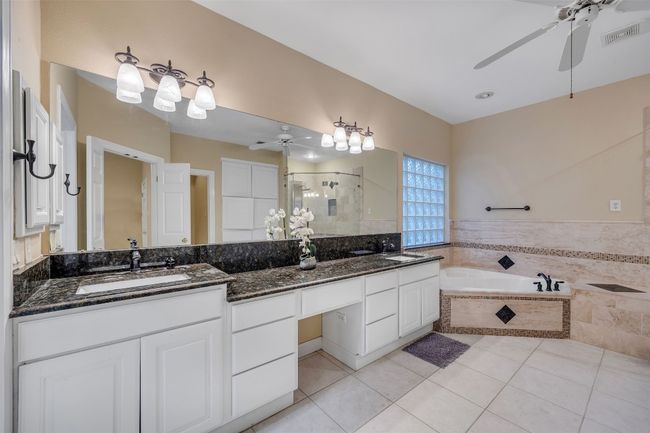 Bathroom with ceiling fan, a stall shower, double vanity, and tile patterned floors | Image 23