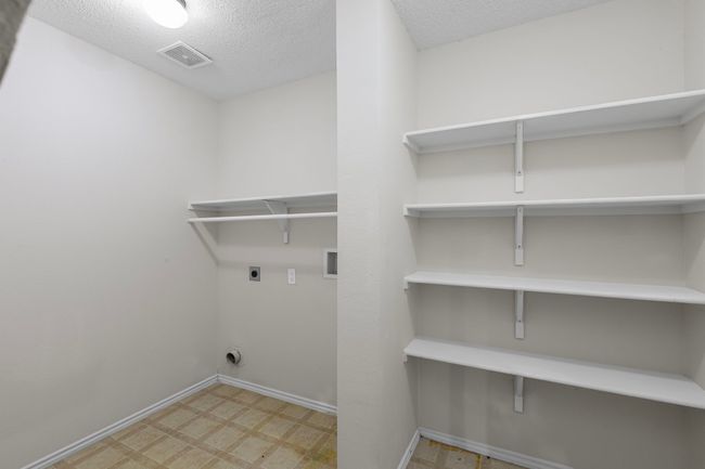 Laundry area with electric dryer hookup, tile patterned floors, and a textured ceiling | Image 21
