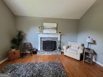 Great room featuring vaulted ceiling, stacked stone fireplace, hardwood flooring, ceilingfan and arched doorway to kitchen | Image 3