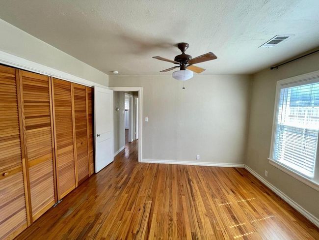 Unfurnished bedroom with wood finished floors, baseboards, a closet, a textured ceiling, and ceiling fan | Image 10