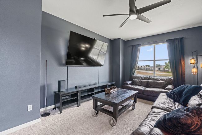 Living area with carpet floors, ceiling fan, baseboards, and a textured wall | Image 21