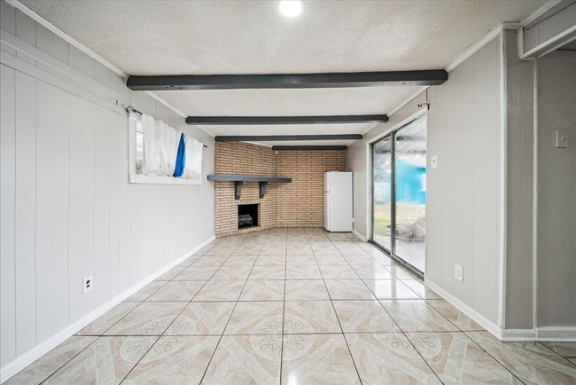 Unfurnished living room featuring healthy amount of natural light, beamed ceiling, a fireplace, and a textured ceiling | Image 13