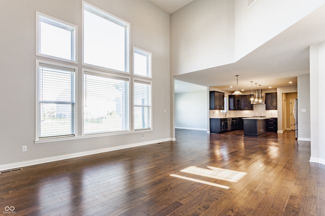 unfurnished living room with dark wood-style flooring, a notable chandelier, visible vents, and baseboards | Image 15