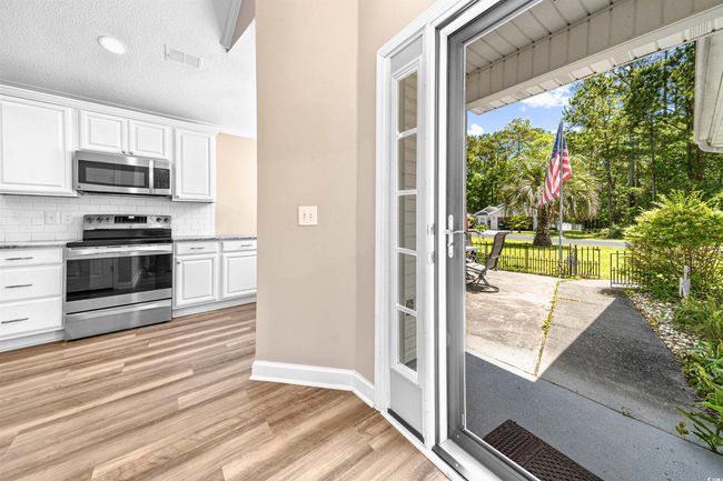 Kitchen with appliances with stainless steel finishes, light wood finished floors, white cabinetry, tasteful backsplash, and visible vents | Image 19
