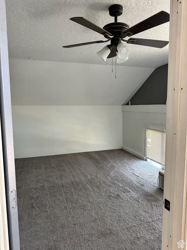 Bonus room with dark colored carpet, a textured ceiling, vaulted ceiling, and ceiling fan | Image 23