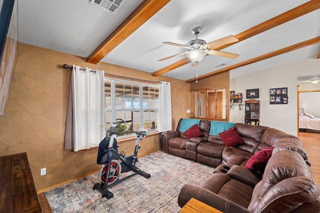 Living room featuring visible vents, wood finished floors, ceiling fan, and lofted ceiling with beams | Image 20